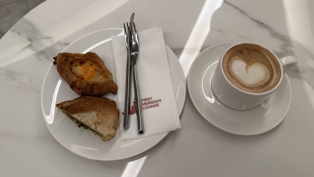 マニラ空港のFirst Meridian Loungeでとった朝食。サンドイッチと卵入りクロワッサン、カプチーノが大理石のテーブルに並んでいる