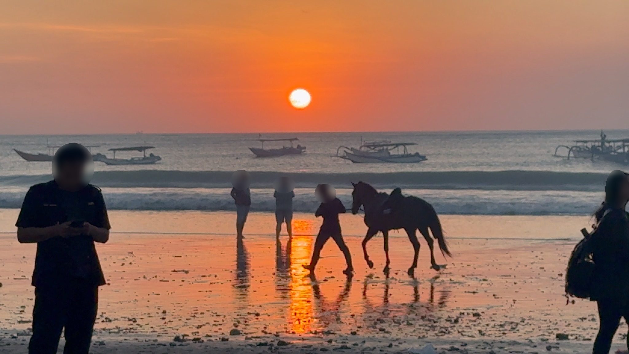 ジンバランの夕焼け。赤く染まる砂浜と、沖に浮かぶ船
