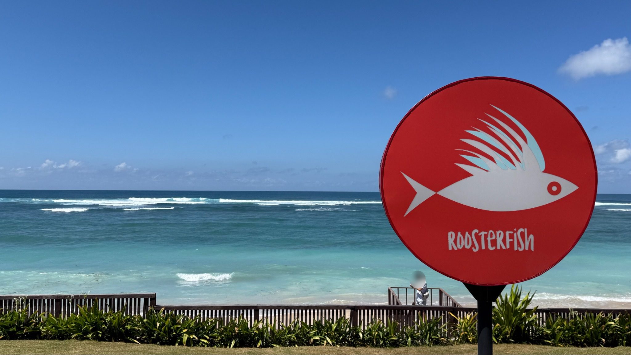 Roosterfish Beach Clubの看板と、パンダワ・ビーチの青い海